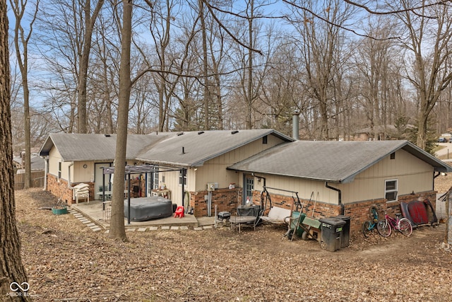 back of property with a patio area, a shingled roof, stone siding, and brick siding