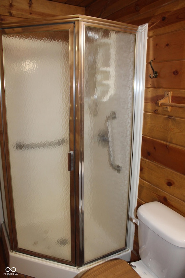 full bathroom featuring toilet, wooden walls, and a shower stall