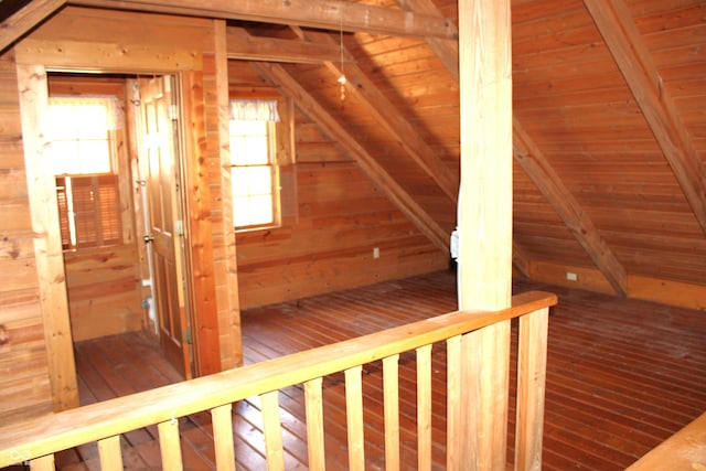 additional living space featuring a wealth of natural light, wood-type flooring, wooden walls, and lofted ceiling with beams