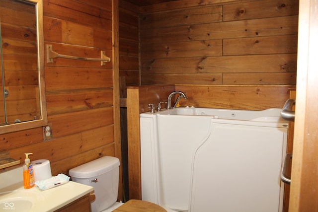 full bath with vanity, wooden walls, toilet, and a bathing tub