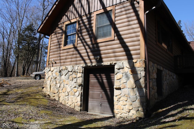 view of side of home with stone siding and faux log siding