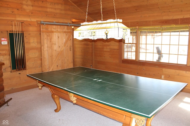 playroom with vaulted ceiling, a barn door, wood walls, and carpet flooring