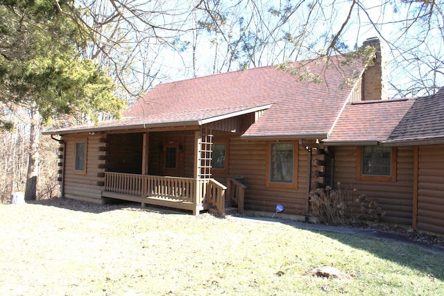 view of front of property with a front yard, roof with shingles, a chimney, and log siding