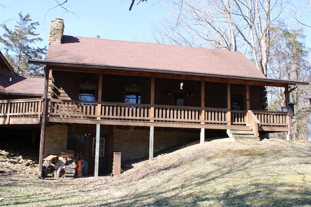 rear view of house with log exterior, a shingled roof, and a chimney