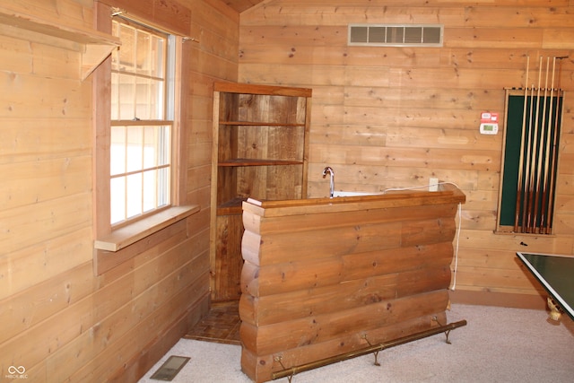 bar featuring vaulted ceiling, visible vents, wood walls, and carpet flooring