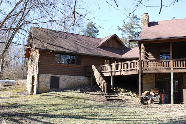 view of side of home with roof with shingles, stairs, a chimney, and a wooden deck