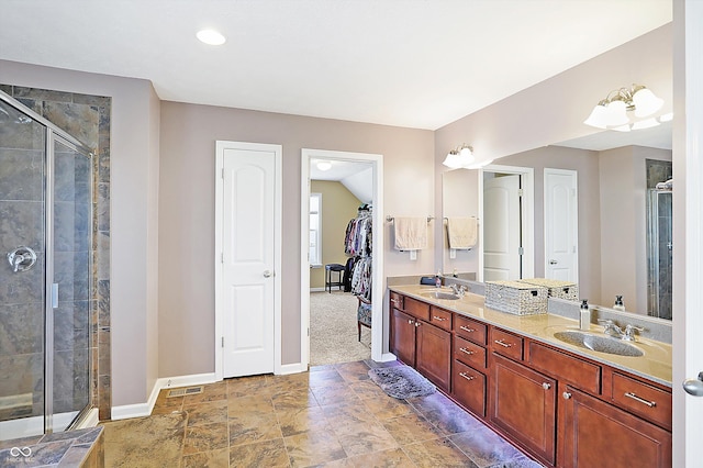 full bath featuring a sink, baseboards, double vanity, a stall shower, and a walk in closet