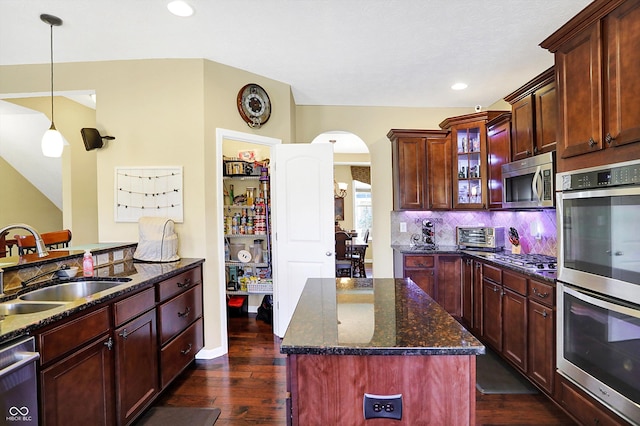 kitchen featuring dark wood finished floors, decorative backsplash, appliances with stainless steel finishes, glass insert cabinets, and a sink