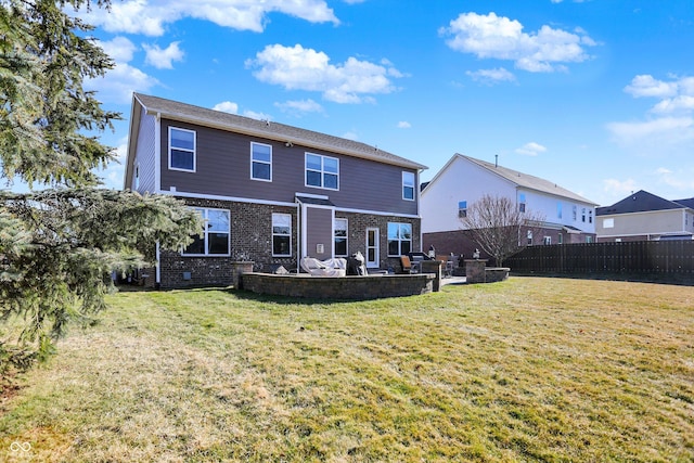 back of house featuring brick siding, fence, and a yard