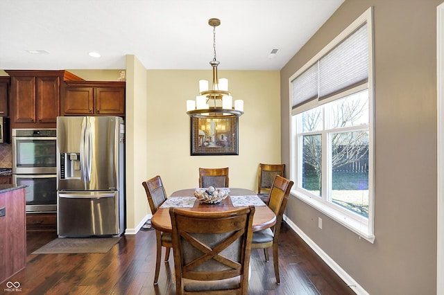 dining room with dark wood-type flooring, an inviting chandelier, and baseboards