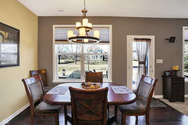 dining space featuring wood finished floors, visible vents, baseboards, and an inviting chandelier