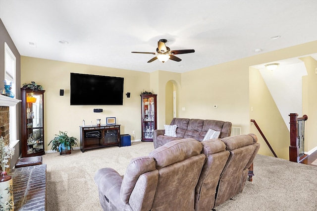 carpeted living area with arched walkways, ceiling fan, visible vents, and baseboards