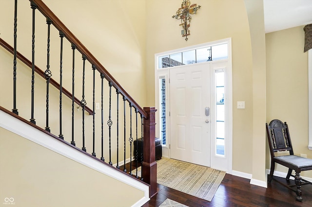 foyer featuring dark wood-style floors, baseboards, stairs, and a healthy amount of sunlight