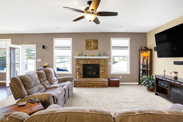 carpeted living area with ceiling fan, a fireplace, and baseboards