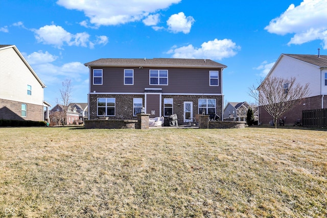 rear view of house featuring brick siding, a lawn, and fence