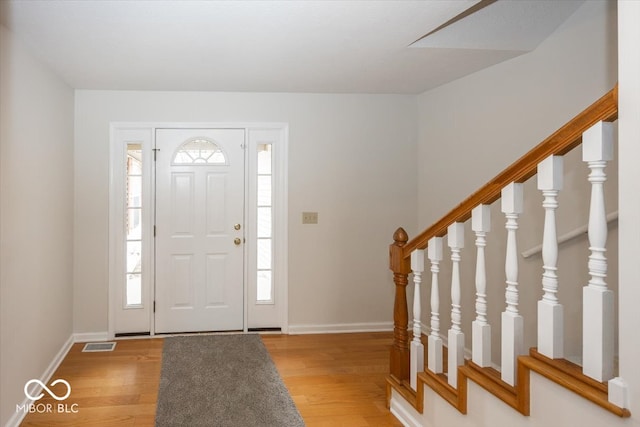 foyer with light wood-type flooring, baseboards, stairs, and visible vents