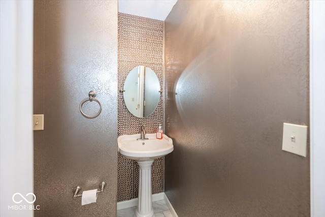 bathroom with a textured wall and baseboards