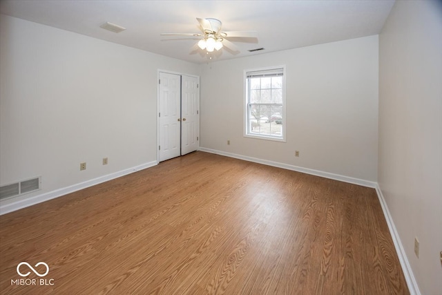 empty room with light wood-type flooring, baseboards, visible vents, and a ceiling fan