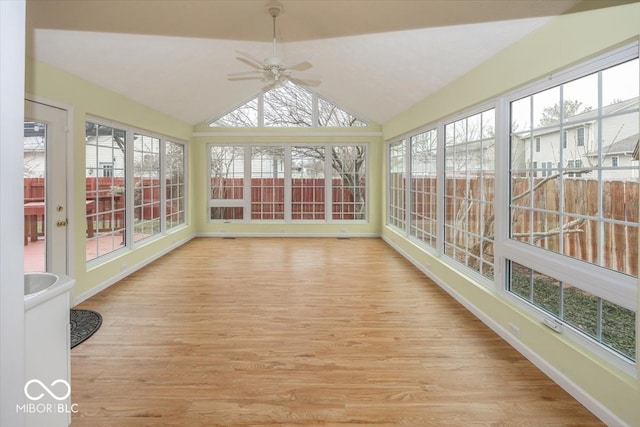 unfurnished sunroom featuring lofted ceiling, plenty of natural light, and ceiling fan