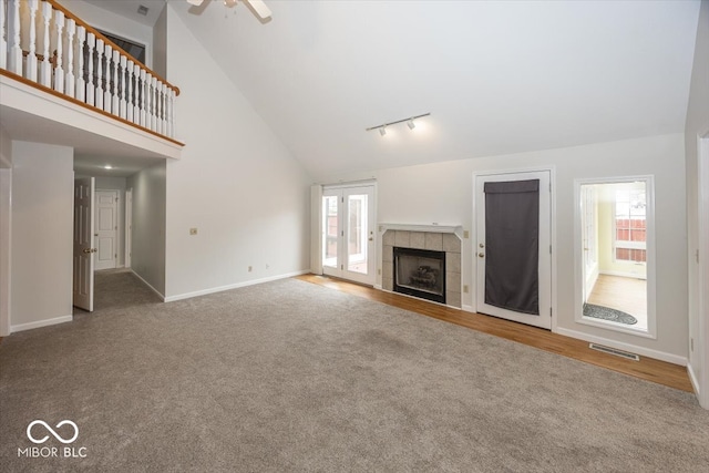 unfurnished living room featuring a healthy amount of sunlight, carpet floors, visible vents, and a tile fireplace