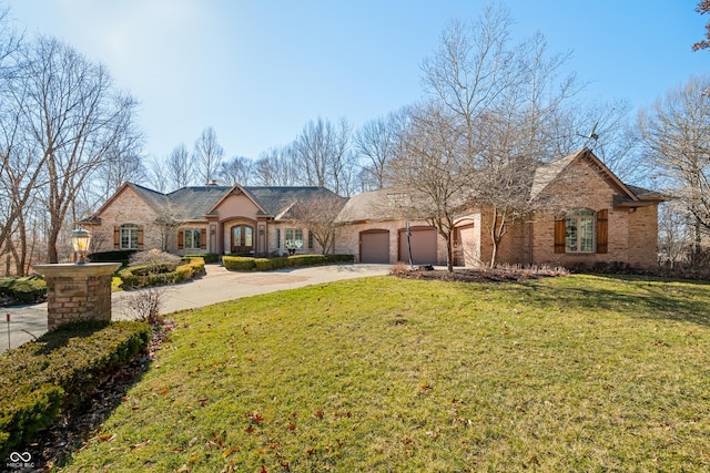 french provincial home featuring driveway, a garage, a chimney, a front lawn, and brick siding