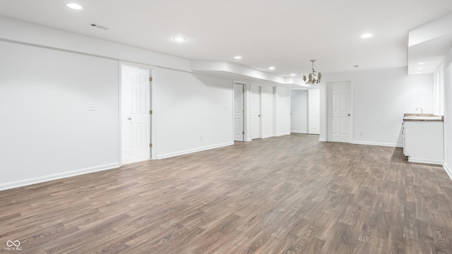 unfurnished living room with recessed lighting, baseboards, wood finished floors, and a sink