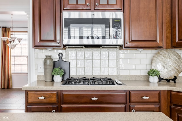 kitchen featuring glass insert cabinets, backsplash, and appliances with stainless steel finishes