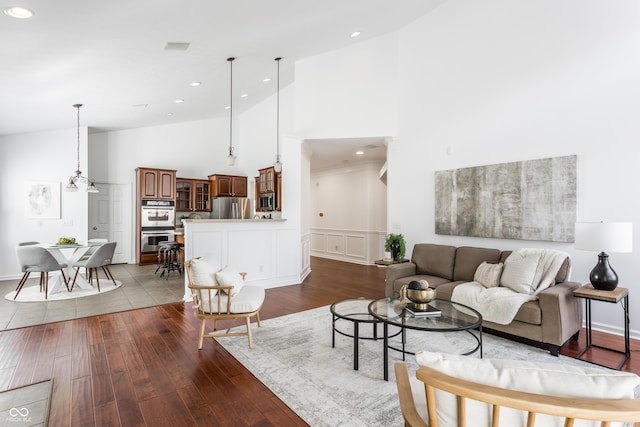 living room with recessed lighting, high vaulted ceiling, dark wood-style floors, and a decorative wall