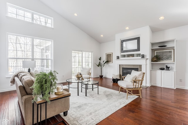 living area with a tiled fireplace, recessed lighting, dark wood-style flooring, and baseboards