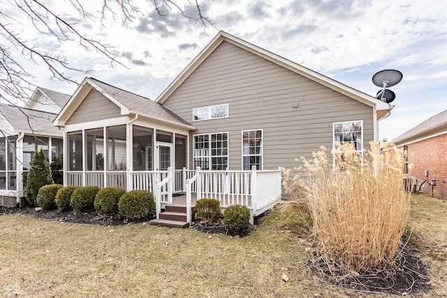 back of house featuring a lawn and a sunroom