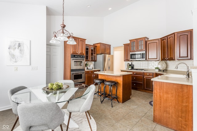 kitchen featuring a kitchen bar, a sink, a center island, stainless steel appliances, and decorative backsplash