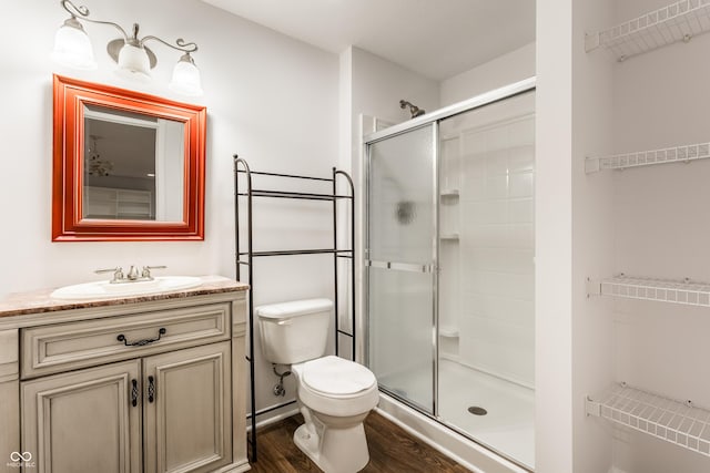 bathroom with vanity, toilet, wood finished floors, and a shower stall