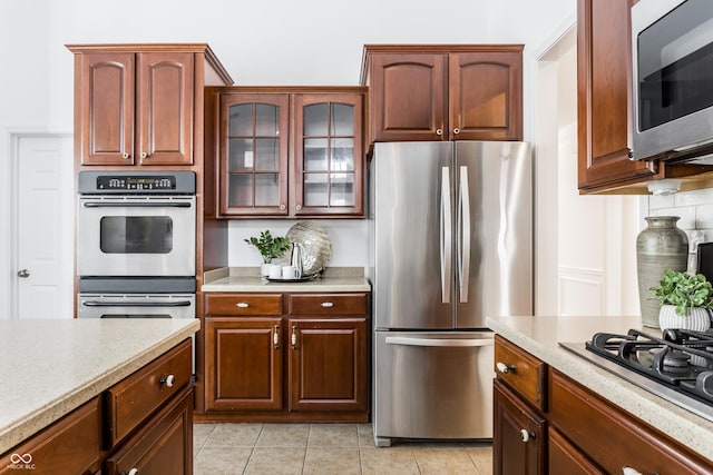 kitchen with glass insert cabinets, appliances with stainless steel finishes, and light countertops