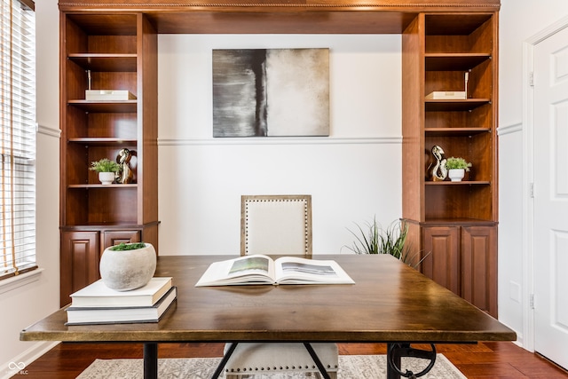 office space featuring dark wood-type flooring and built in shelves