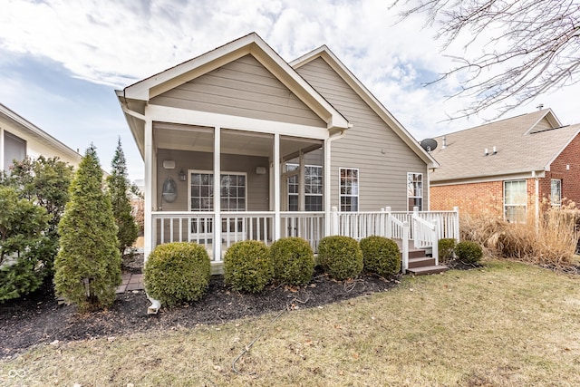 rear view of property featuring covered porch and a lawn