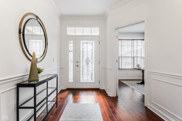 entrance foyer featuring crown molding, a decorative wall, dark wood-style flooring, and wainscoting