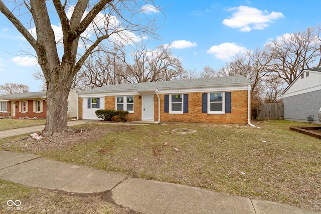 ranch-style house featuring brick siding, roof with shingles, a front yard, and fence