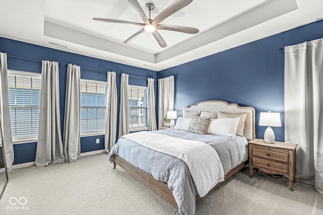 bedroom with visible vents, baseboards, a tray ceiling, carpet flooring, and a ceiling fan