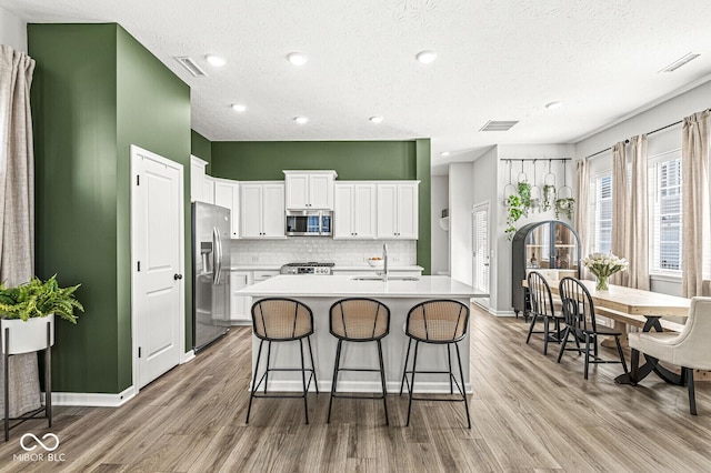 kitchen featuring visible vents, a sink, stainless steel appliances, light wood-style floors, and light countertops