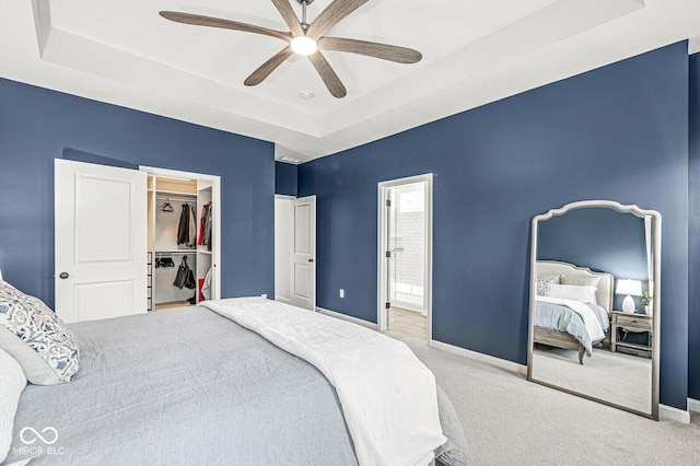 bedroom featuring a tray ceiling, baseboards, carpet floors, and ceiling fan