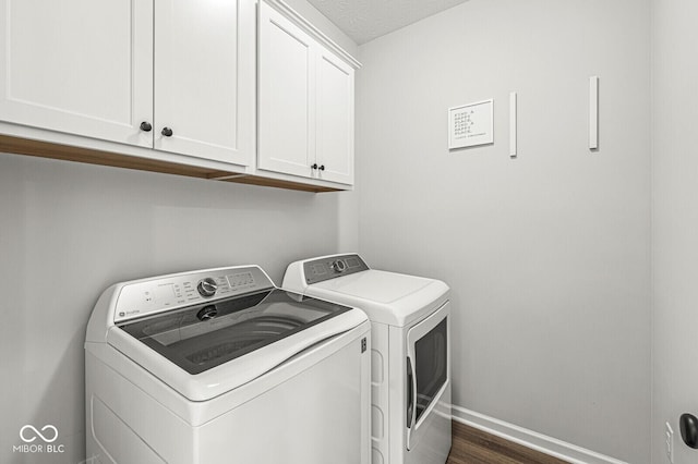 laundry room featuring baseboards, cabinet space, dark wood-style flooring, and washer and clothes dryer