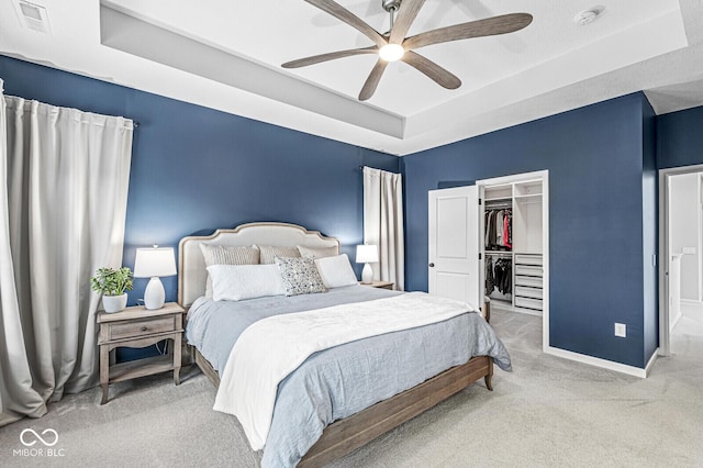 bedroom with visible vents, a tray ceiling, carpet floors, baseboards, and a spacious closet