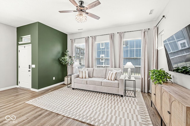 living area featuring ceiling fan, visible vents, baseboards, and light wood-style flooring