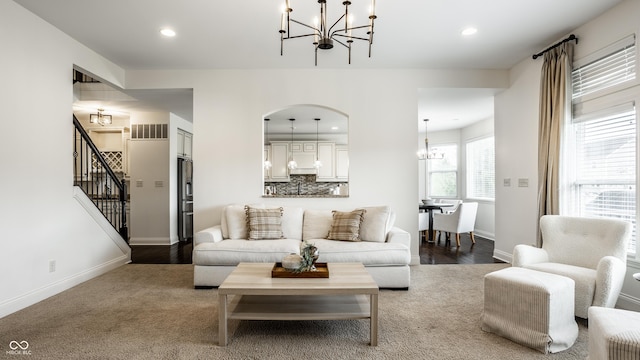 living area with arched walkways, stairs, baseboards, a chandelier, and recessed lighting