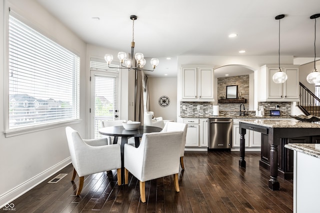 dining area featuring arched walkways, baseboards, a notable chandelier, and dark wood finished floors