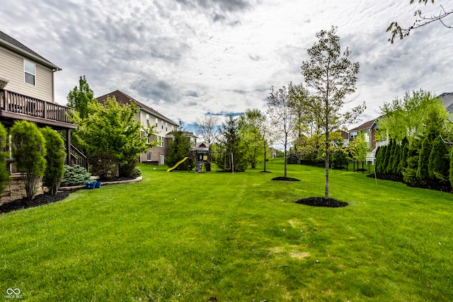 view of yard featuring a playground, a wooden deck, and a residential view