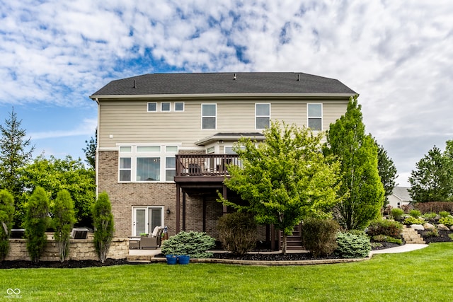 rear view of property with a lawn, a deck, and brick siding