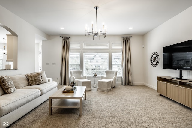 living room with an inviting chandelier, light colored carpet, arched walkways, recessed lighting, and baseboards