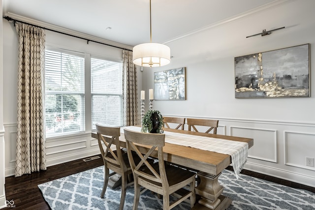 dining space with dark wood-style flooring, wainscoting, ornamental molding, and a decorative wall