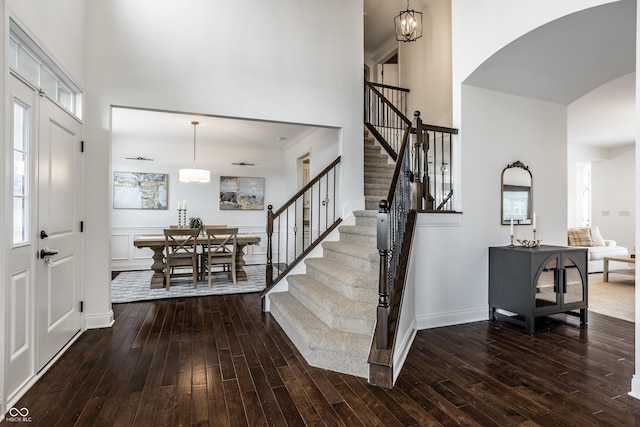 entrance foyer featuring wood-type flooring, arched walkways, a towering ceiling, and stairway